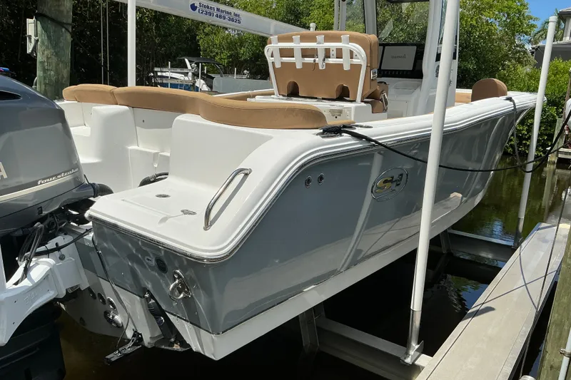 The Image of A 2021 Sea Hunt Ultra 255SE boat on a lift, featuring a beige seating area. - 0