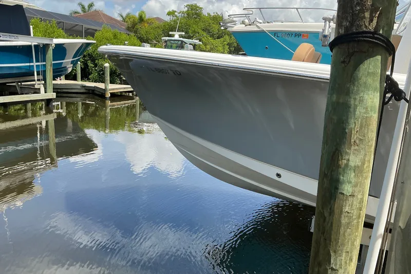 Slide: The Image of 2021 Sea Hunt Ultra 255SE boat docked in a serene marina setting. - 37