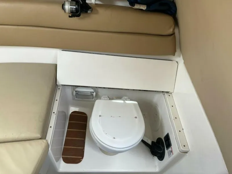Slide: The Image of A small white boat toilet in a beige interior with cushions and wood accents. - 11
