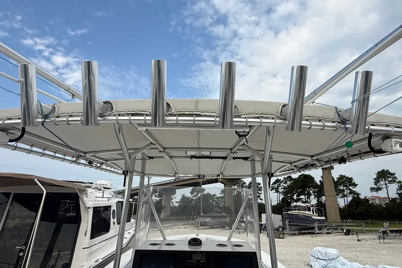 Slide: The Image of 2007 SeaCraft SC 32 Master Angler boat with rod holders and canopy, docked under a blue sky. - 38