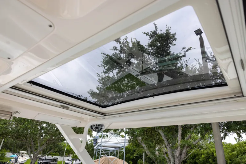 Slide: The Image of The image shows the glass roof of a Chaparral 300 OSX boat with trees in the background. - 17