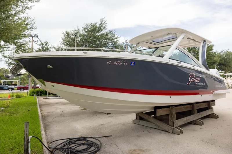 The Image of Chaparral 300 OSX 2023 on a stand, dark gray with red stripe, parked outdoors. - 1