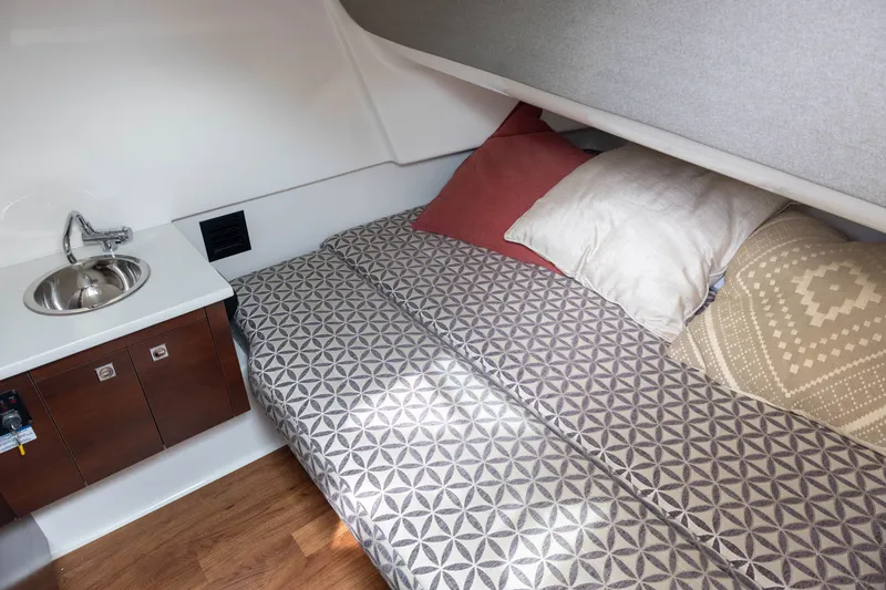 Slide: The Image of Interior of the 2023 Chaparral 300 OSX with a cozy bed, pillows, and a small sink. - 14