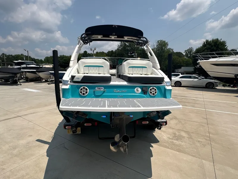 Slide: The Image of The image shows a 2020 Regal LS4 Surf boat in a parking area. It has a turquoise rear and large deck. - 10