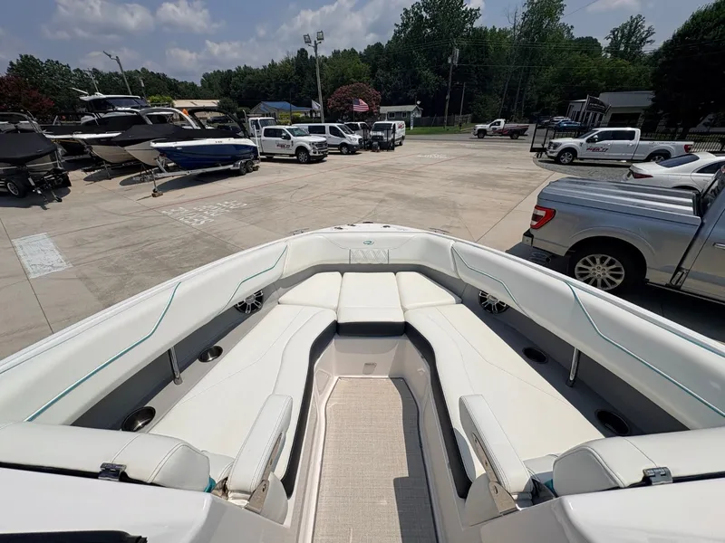 Slide: The Image of 2020 Regal LS4 Surf with spacious bow seating and white upholstery, parked in a boat lot. - 21