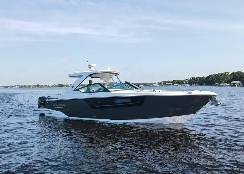 Slide: The Image of 2023 Monterey 385 Super Sport boat cruising on a calm lake under a clear sky. - 4