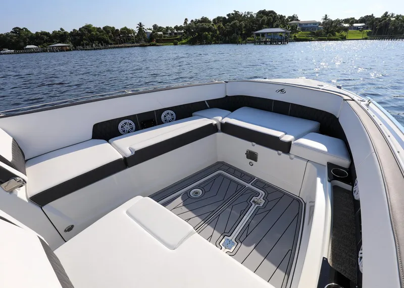 Slide: The Image of 2023 Monterey 385 Super Sport boat interior with spacious seating, on a serene water backdrop. - 26