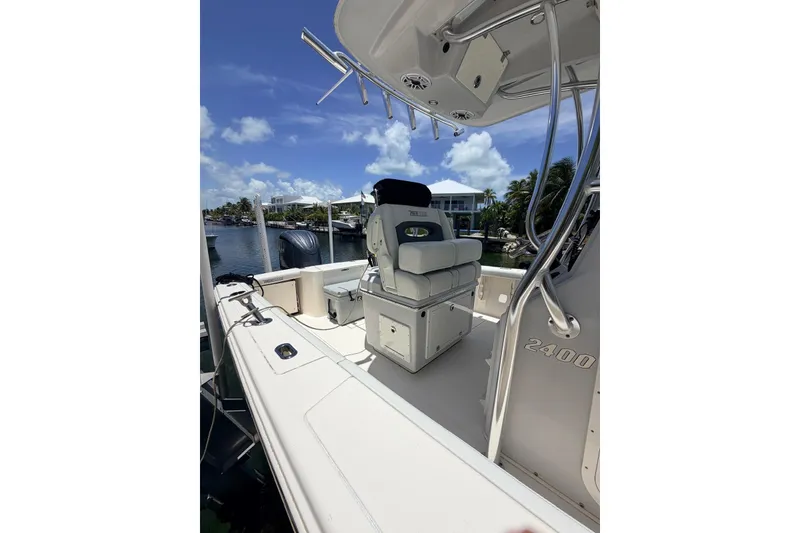 Slide: The Image of 2023 Pathfinder 2400 Open boat interior with seating and rod holders, docked by a scenic waterfront. - 3