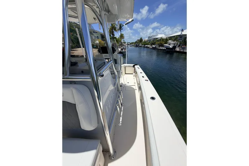Slide: The Image of 2023 Pathfinder 2400 Open boat docked by a scenic canal under a clear blue sky. - 8