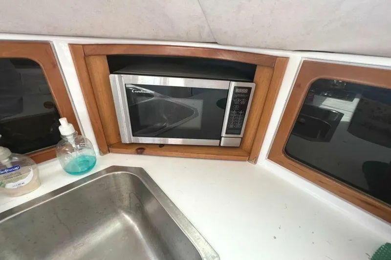 Slide: The Image of The yacht's kitchen features a built-in microwave, a sink, and windows. - 35