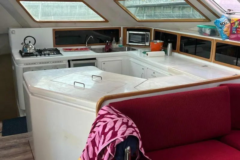 Slide: The Image of Interior of a 1995 Voyage Yachts Mayotte with modern kitchen, red sofa, and large windows. - 14