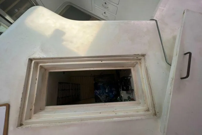 Slide: The Image of An open storage compartment on a boat with white surfaces and a handle on the side. - 38