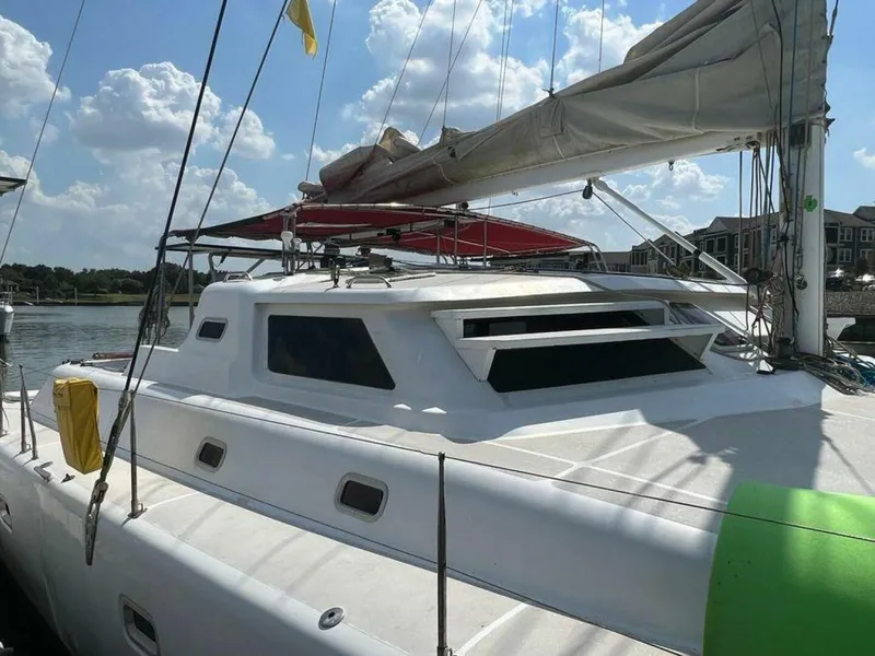 Slide: The Image of A 1995 Voyage Yachts Mayotte catamaran on the water, featuring a white deck and red sunshade. - 3