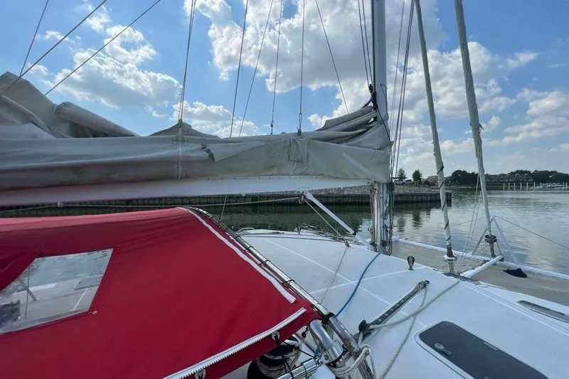 Slide: The Image of The image shows the deck of a sailboat with red covers and sails under a blue sky. - 9