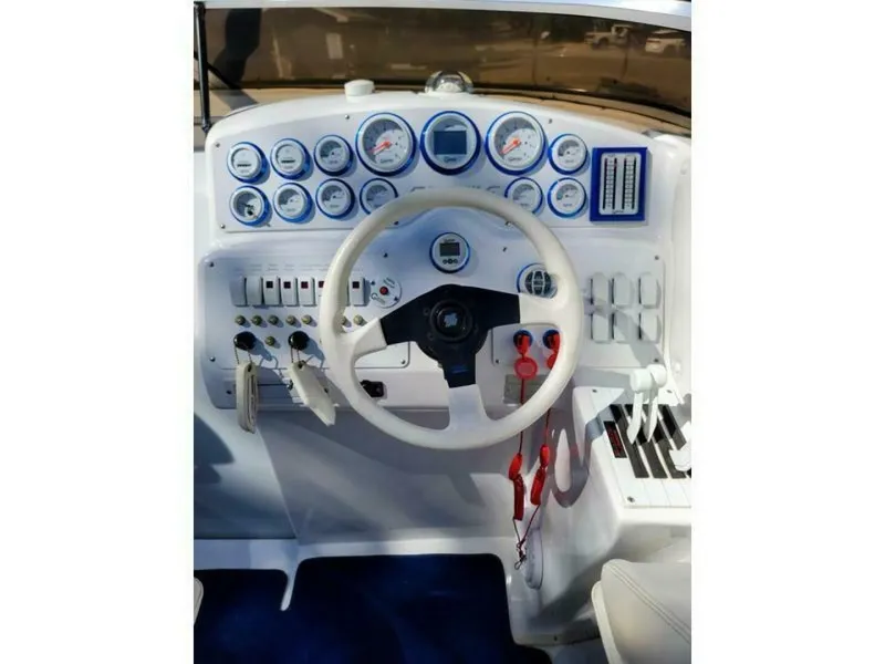 Slide: The Image of The image shows the cockpit of a 2002 Profile 33 V boat with a white steering wheel and numerous gauges. - 2