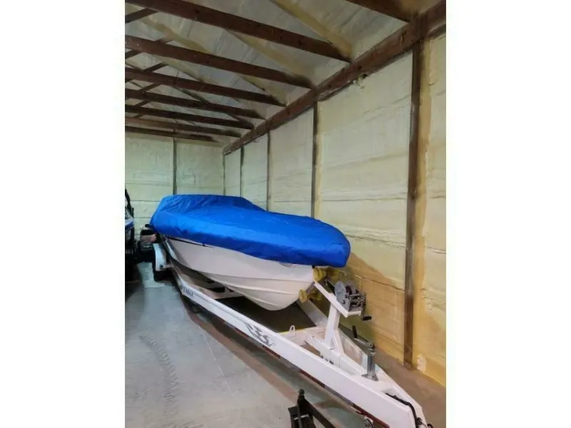 Slide: The Image of A 2002 Profile 33 V boat with a blue cover sits on a trailer in a shed. - 8