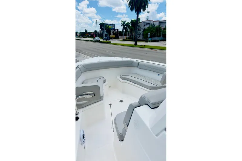 Slide: The Image of 2026 Pursuit S 288 Sport boat interior with cushioned seating, parked near a road. - 8