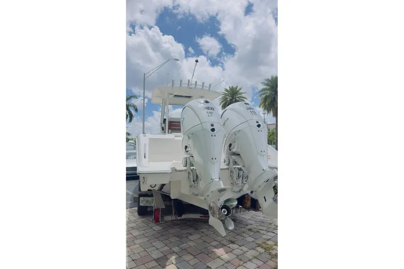 Slide: The Image of 2026 Pursuit S 288 Sport boat with dual outboard engines, parked on a sunny day. - 14