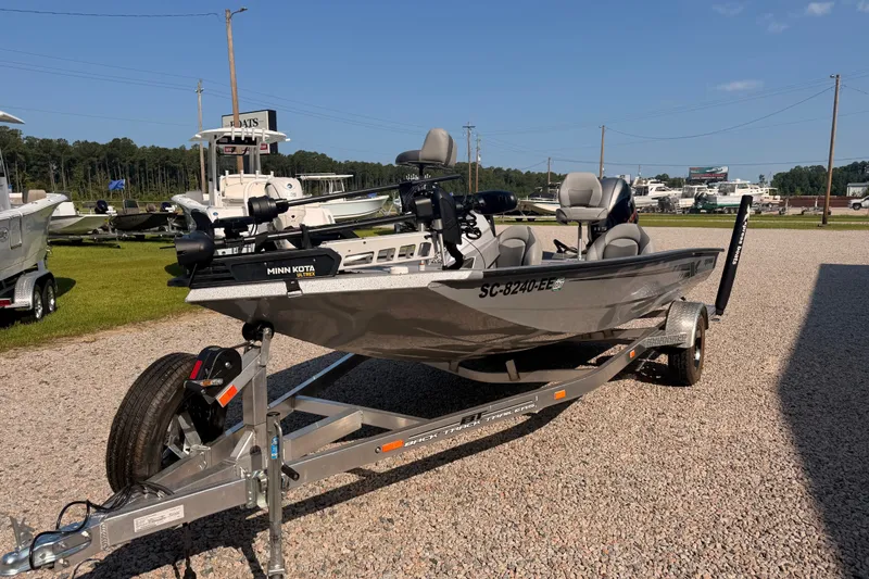 Slide: The Image of 2023 Xpress Boats H18 Bass on trailer, featuring Minn Kota motor, parked outdoors. - 2