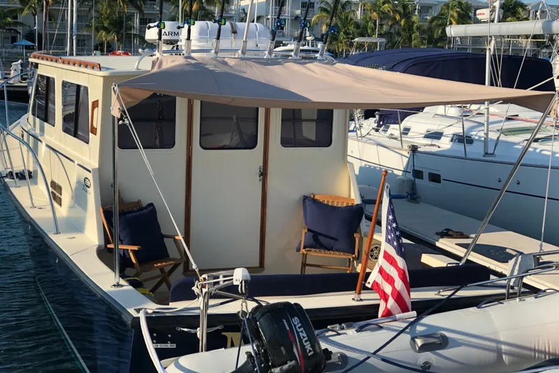Slide: The Image of 2018 Eastern 35 Casco Bay boat docked, featuring a shaded seating area and American flag. - 10