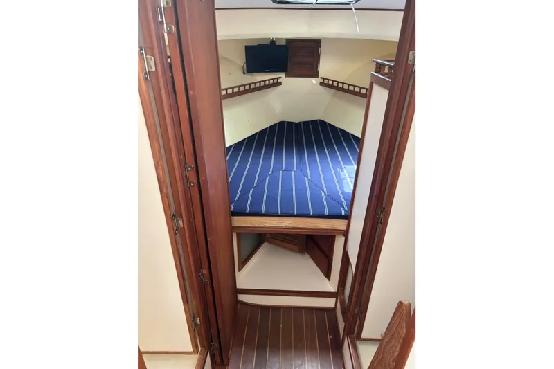 Slide: The Image of 2018 Eastern 35 Casco Bay cabin interior with blue-striped bedding and wooden accents. - 20
