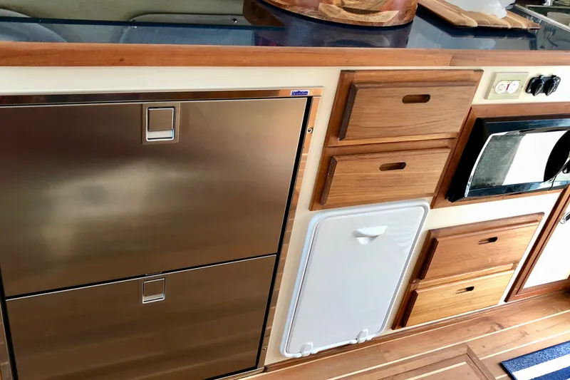 Slide: The Image of Interior of 2018 Eastern 35 Casco Bay boat with stainless steel fridge and wooden cabinetry. - 16