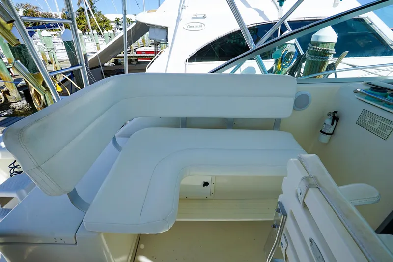 Slide: The Image of 1997 Tiara Yachts 3500 Express interior seating with white cushions and marina background. - 39