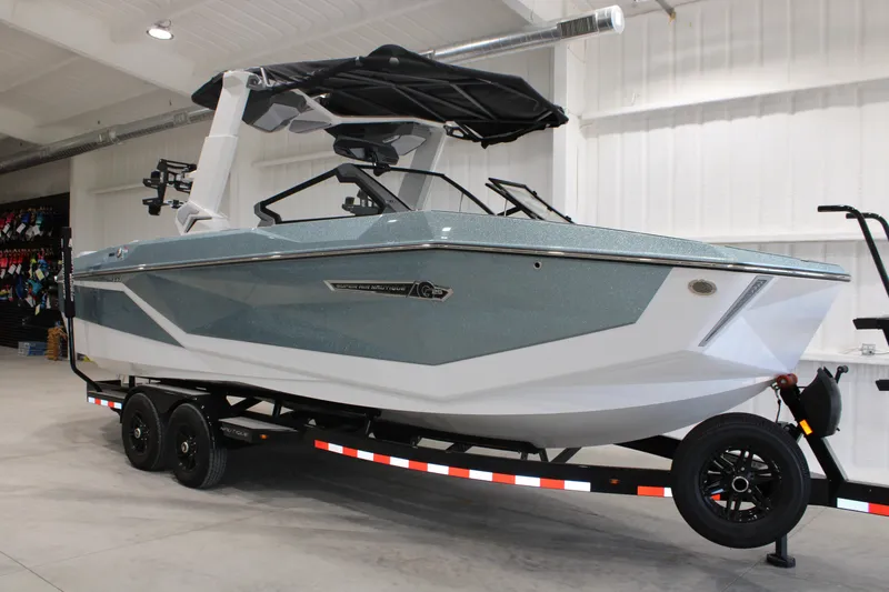 The Image of 2026 Nautique Super Air Nautique G25 boat on trailer in showroom. - 1