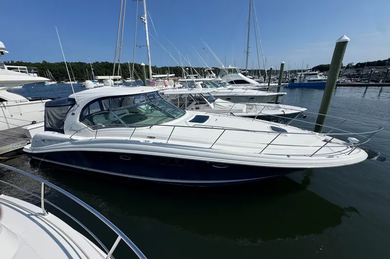 The Image of 2006 Sea Ray 44 Sundancer yacht docked at marina under clear blue sky. - 1