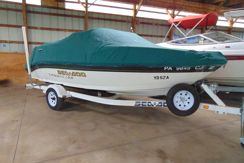 Slide: The Image of 2001 Sea-Doo Utopia 185 boat covered on trailer in storage facility. - 2