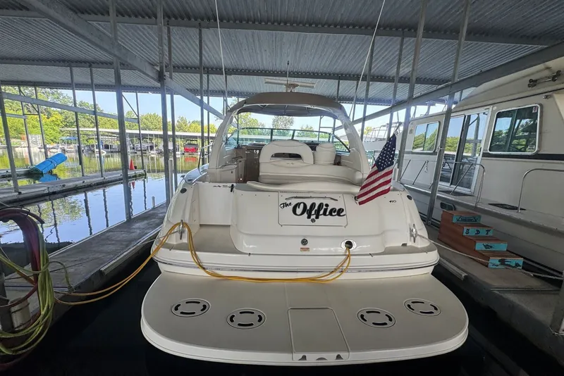 Slide: The Image of 2003 Sea Ray 410 Sundancer docked, rear view with American flag, under covered marina. - 15