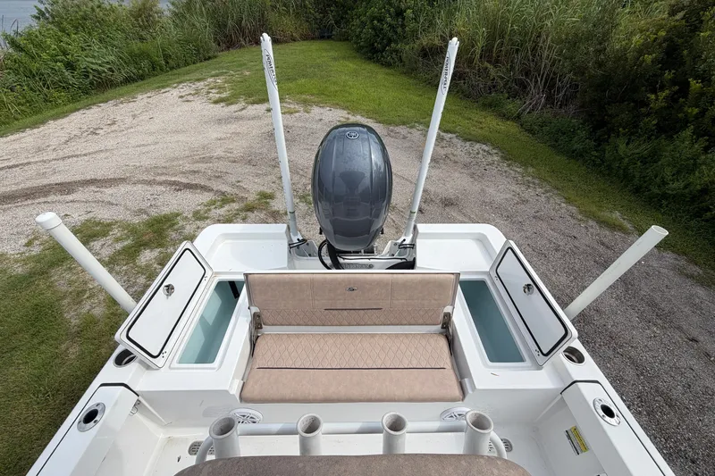 Slide: The Image of 2019 Sportsman Masters 227 Bay Boat with open storage compartments and motor, parked on grass. - 8