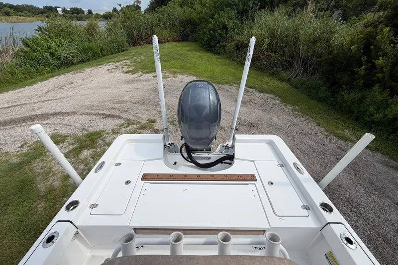 Slide: The Image of 2019 Sportsman Masters 227 Bay Boat with motor, docked near lush greenery. - 12