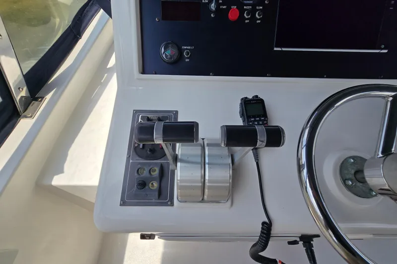 Slide: The Image of Control panel of a 2004 Grand Harbour 58 yacht, featuring throttle levers and steering wheel. - 94