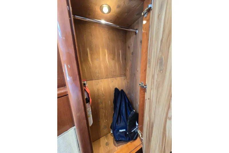 Slide: The Image of Wooden closet interior on a 2004 Grand Harbour 58 yacht, featuring a hanging rod and storage bag. - 70