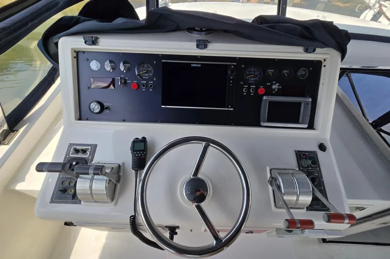 Slide: The Image of Control panel of a 2004 Grand Harbour 58 yacht with steering wheel and navigation instruments. - 90
