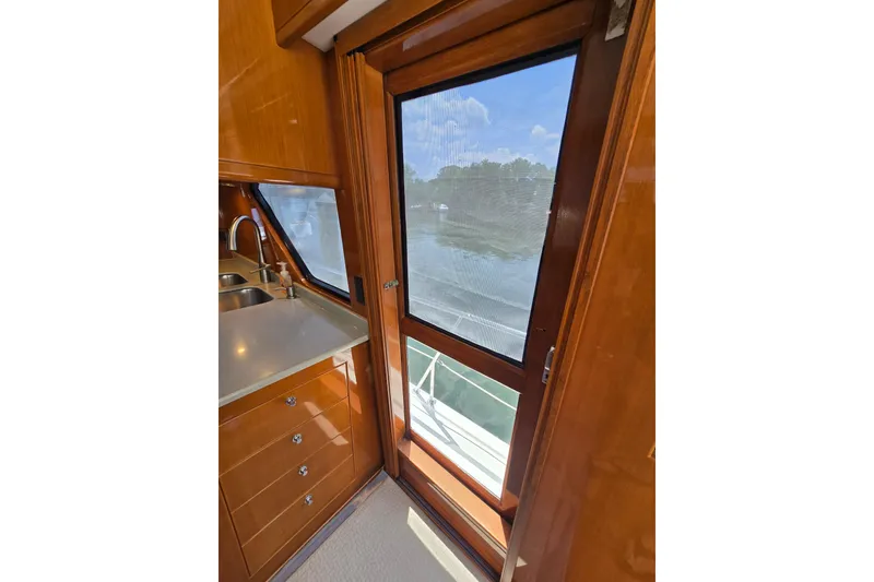 Slide: The Image of Interior view of 2004 Grand Harbour 58 yacht, featuring a sleek kitchen area with wooden cabinetry. - 76