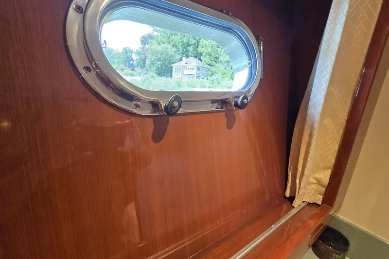 Slide: The Image of Porthole view from 2004 Grand Harbour 58 yacht, featuring wooden interior and curtain. - 54