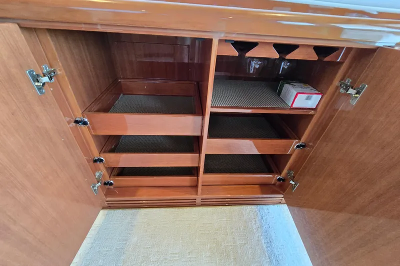 Slide: The Image of Wooden cabinet with open doors, featuring shelves and drawers, inside a 2004 Grand Harbour 58 yacht. - 17