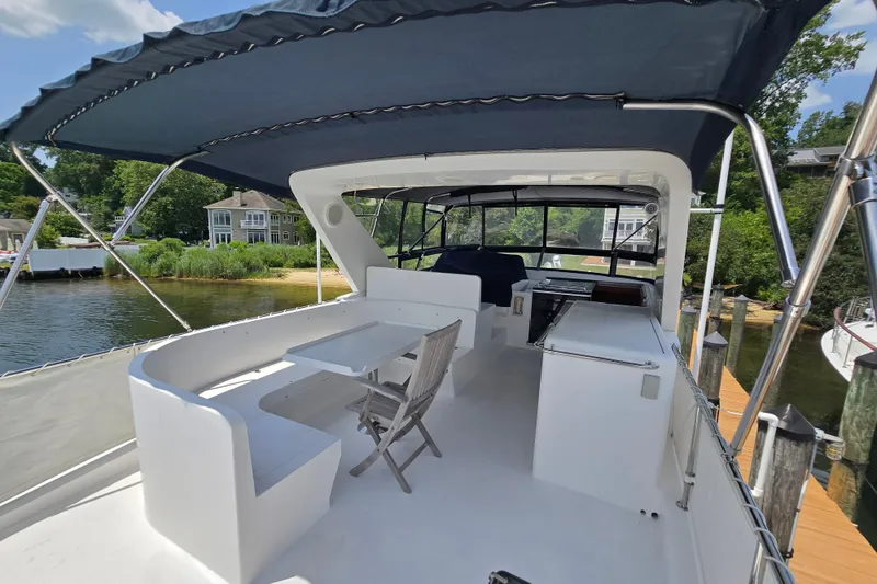Slide: The Image of 2004 Grand Harbour 58 yacht deck with seating and canopy, docked by a scenic waterfront. - 88