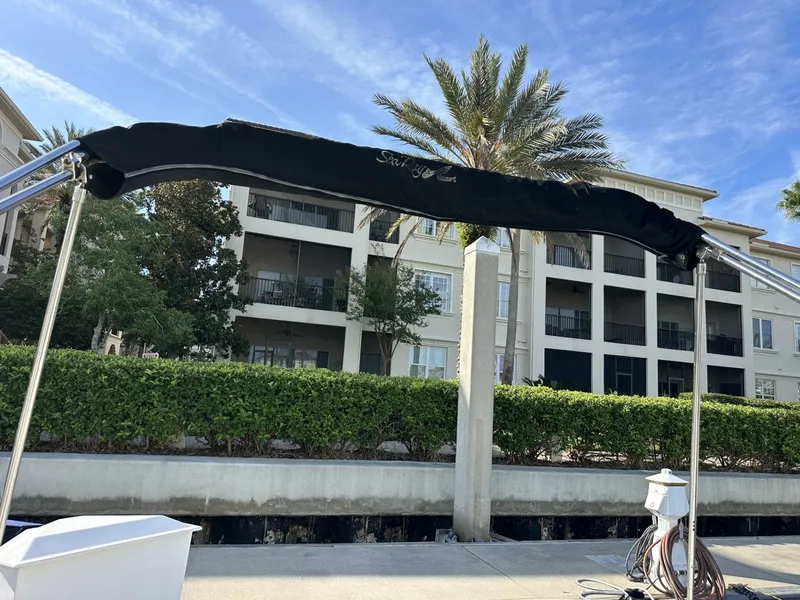 Slide: The Image of A 2010 Sea Ray Sundancer 260 with a black bimini top, docked in front of a building. - 41