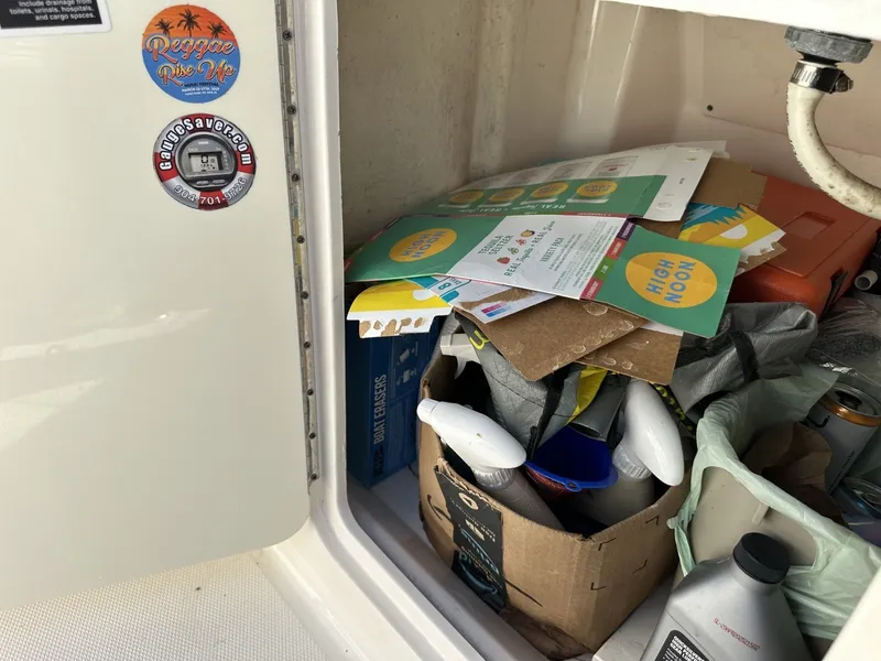 Slide: The Image of A storage compartment on a Sea Ray Sundancer 260 boat with various items and stickers. - 30