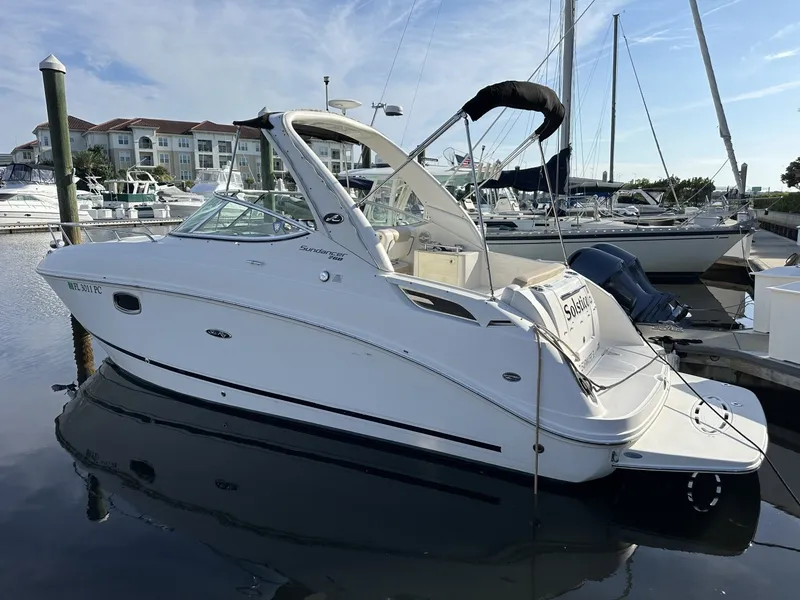 Slide: The Image of A 2010 Sea Ray Sundancer 260 docked at a marina. It features a sleek, white design. - 10