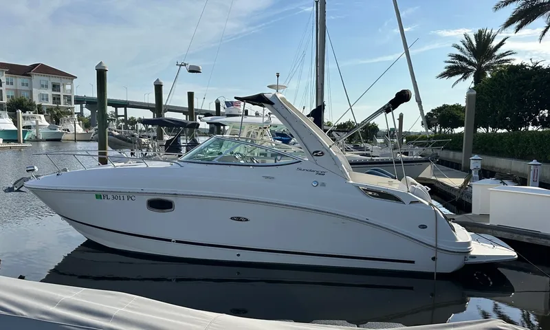 The Image of A 2010 Sea Ray Sundancer 260 docked at a marina. It's a sleek white motorboat. - 0