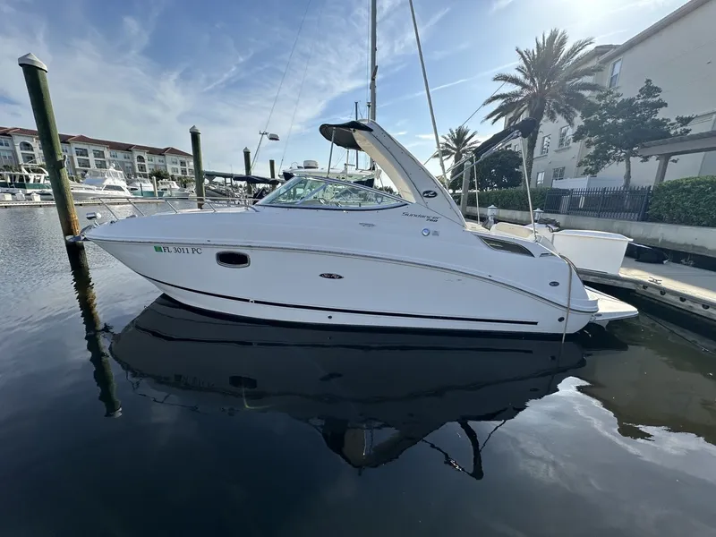 Slide: The Image of A 2010 Sea Ray Sundancer 260 docked in a calm marina, surrounded by palm trees and buildings. - 11