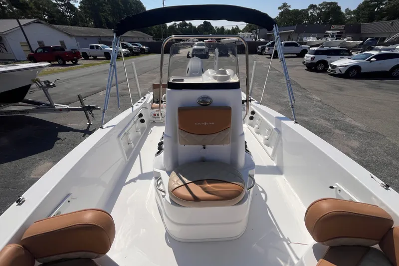 Slide: The Image of 2025 NauticStar 191 Hybrid boat with tan seating, parked outdoors. - 10