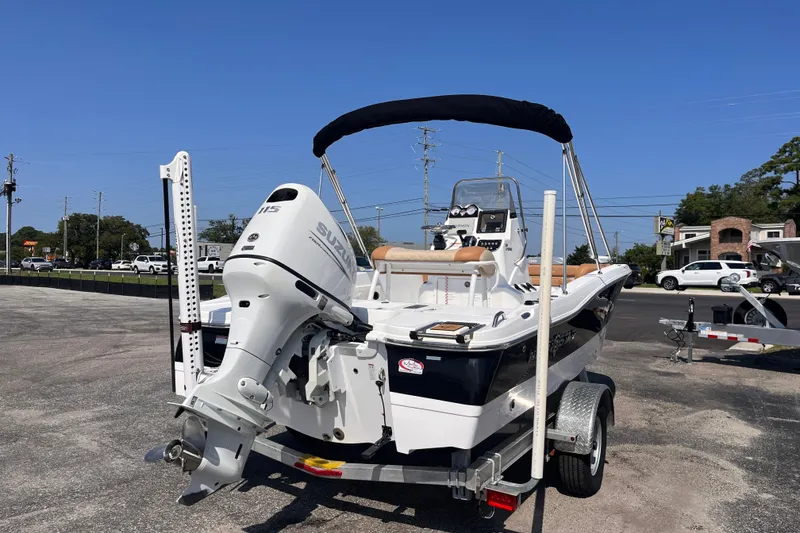 Slide: The Image of 2025 NauticStar 191 Hybrid boat on trailer with Suzuki outboard motor, parked outdoors. - 4