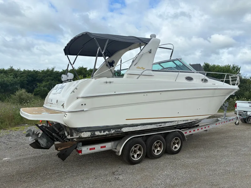 Slide: The Image of A 1998 Sea Ray 290 Sundancer on a trailer, featuring a canopy and spacious deck. - 4