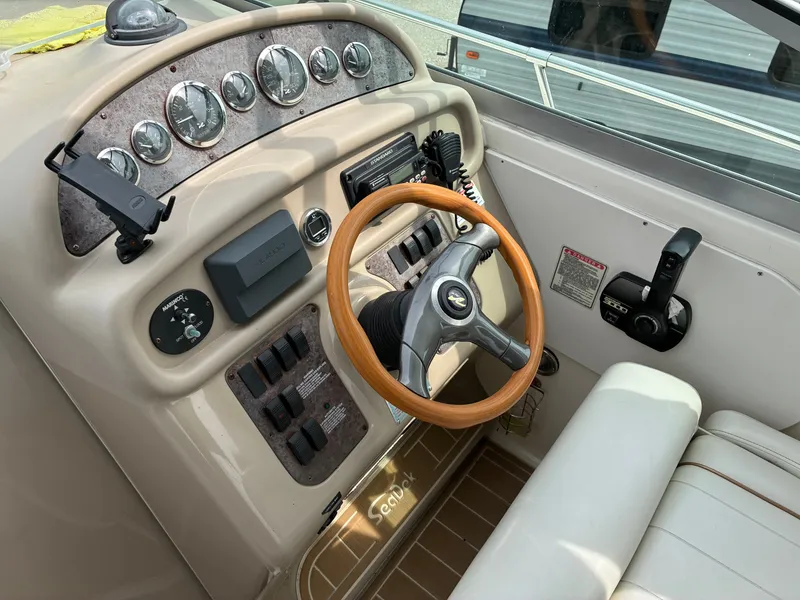Slide: The Image of The image shows the cockpit of a 1998 Sea Ray 290 Sundancer with a wooden steering wheel. - 12