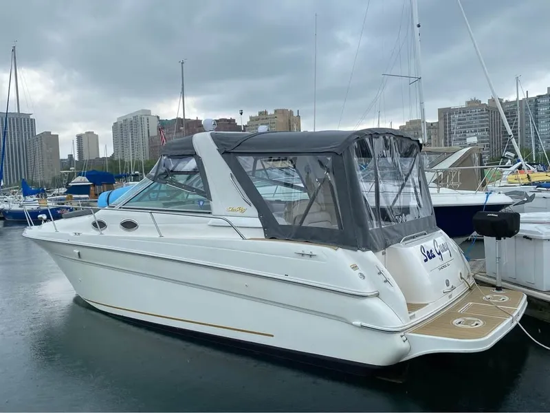 The Image of A 1998 Sea Ray 290 Sundancer docked in a marina, featuring a gray canopy and white hull. - 0